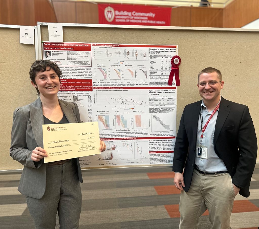 Margo Heston and Tobey Betthauser standing in front of research poster. Margo is holding a representative check award.