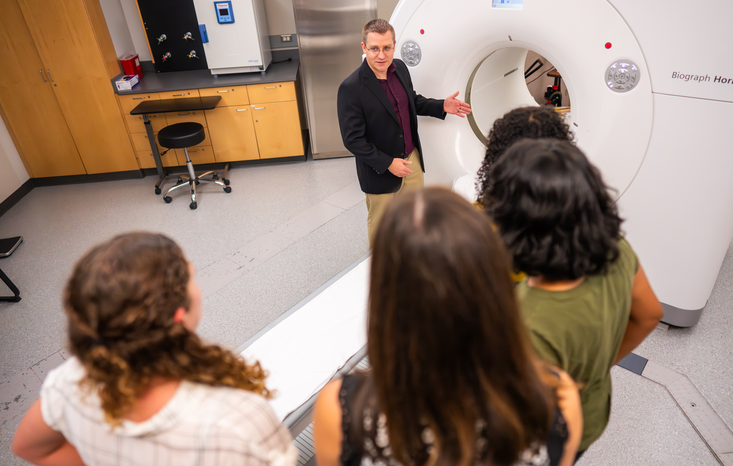 Tobey Betthauser standing in front of GE Biograph Horizon PET/CT Scanner.